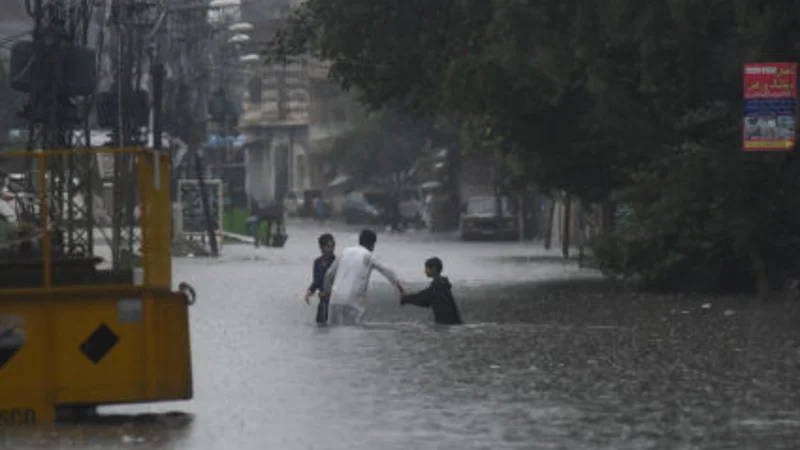 People wade through the flooded street after during the monssoon rain in Rawalpindi